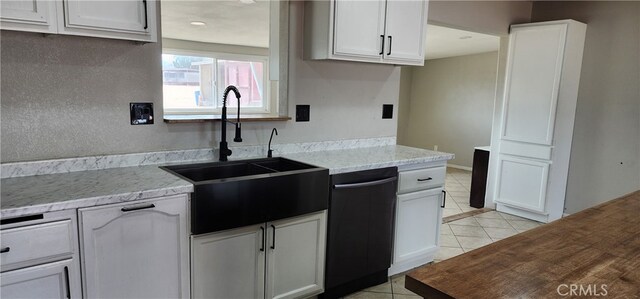 kitchen with sink, dishwasher, white cabinets, and light stone counters