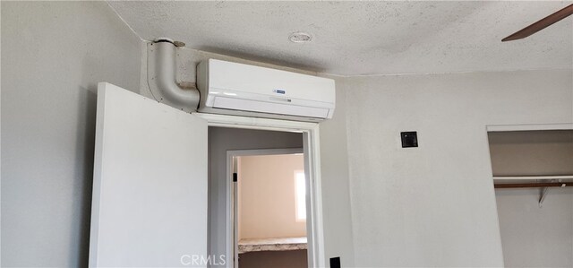 corridor featuring an AC wall unit and a textured ceiling