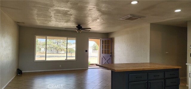 kitchen featuring light tile patterned flooring, a textured ceiling, wooden counters, ceiling fan, and gray cabinets