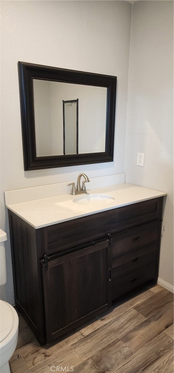 bathroom with vanity, wood-type flooring, and toilet