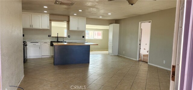 kitchen featuring sink, a center island, light tile patterned floors, white cabinetry, and ceiling fan