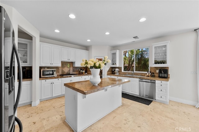 kitchen featuring white cabinetry, a center island, sink, stainless steel appliances, and tasteful backsplash