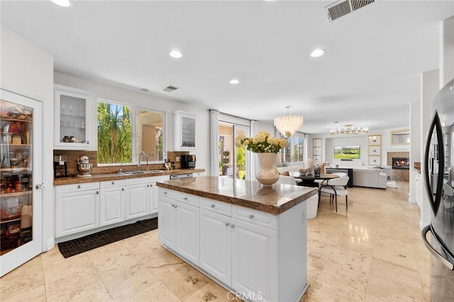 kitchen featuring decorative backsplash, stainless steel fridge, sink, and white cabinets