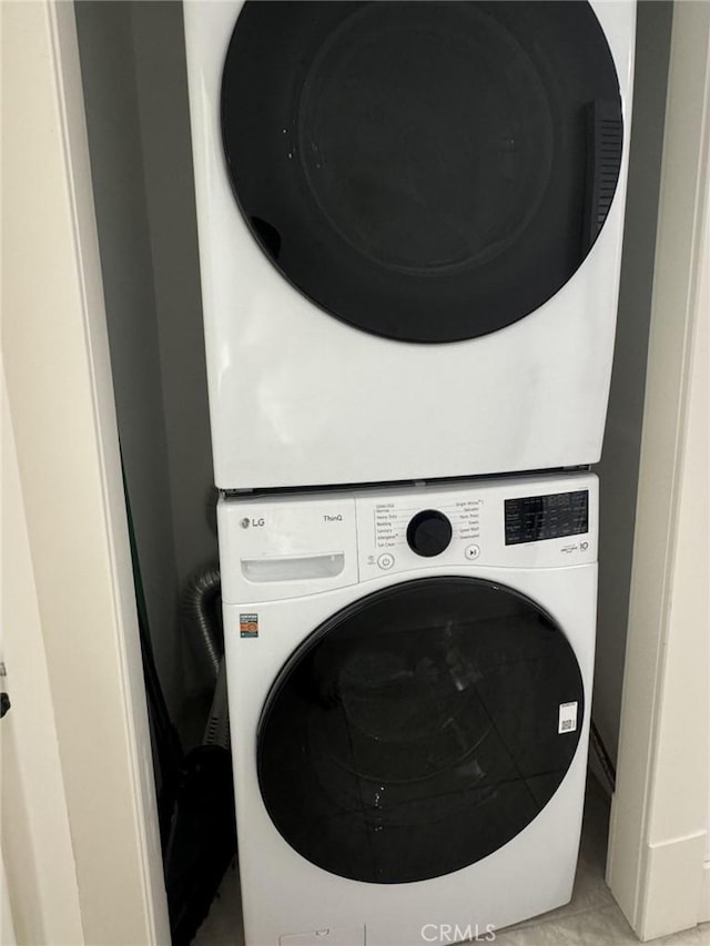 laundry room with tile patterned floors and stacked washing maching and dryer