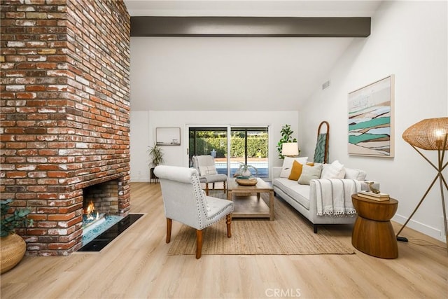 living room with a fireplace, lofted ceiling with beams, and light hardwood / wood-style floors