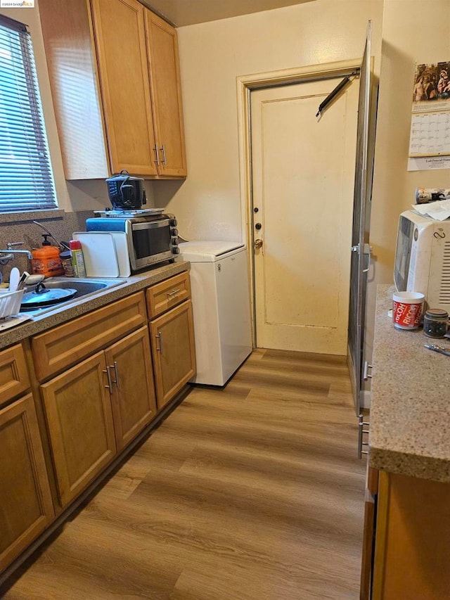 kitchen with light hardwood / wood-style floors, washer / clothes dryer, and sink