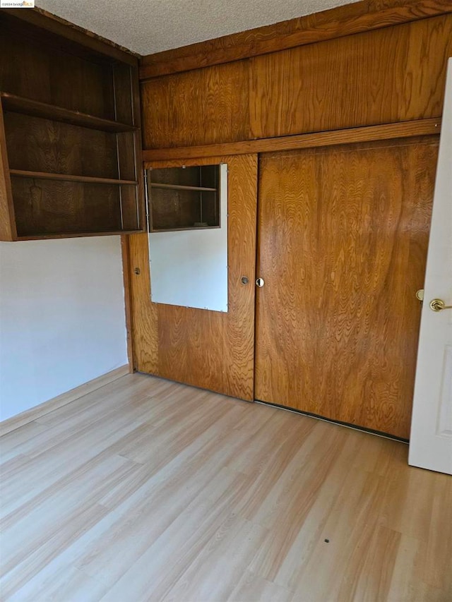 unfurnished bedroom with a closet, a textured ceiling, and light wood-type flooring