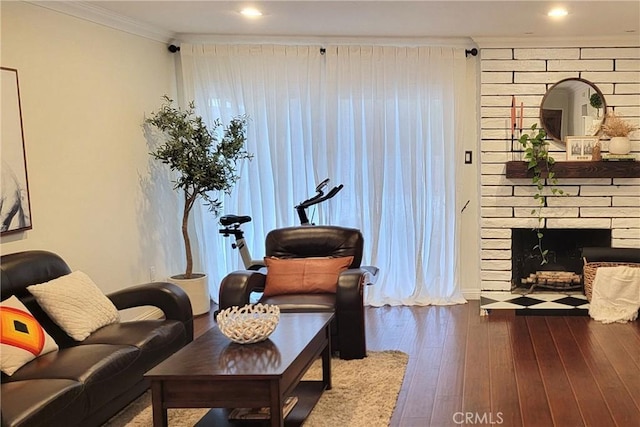 sitting room with a large fireplace, crown molding, and hardwood / wood-style floors