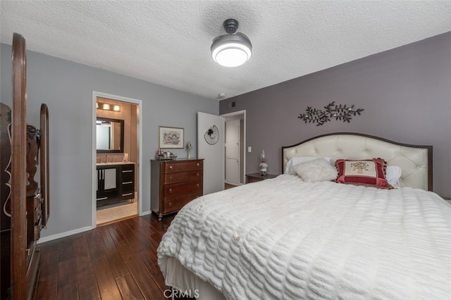 bedroom featuring ensuite bath, dark wood-type flooring, and a textured ceiling