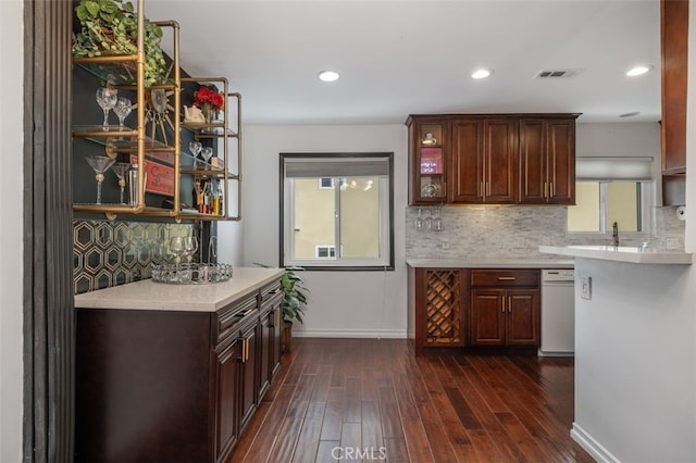 bar featuring dark hardwood / wood-style flooring, backsplash, dark brown cabinets, and dishwasher