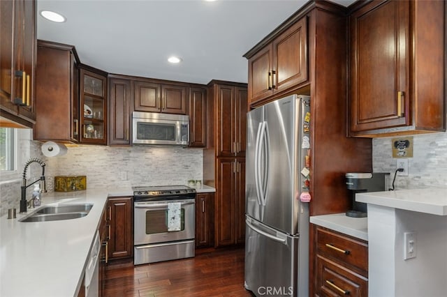 kitchen with dark hardwood / wood-style flooring, sink, tasteful backsplash, and appliances with stainless steel finishes