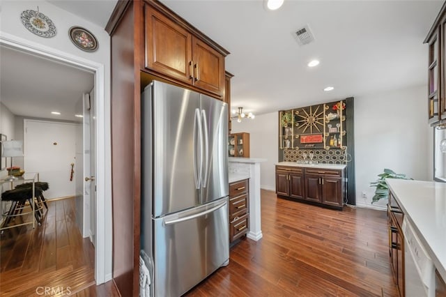 kitchen with stainless steel refrigerator, white dishwasher, dark wood-type flooring, and backsplash