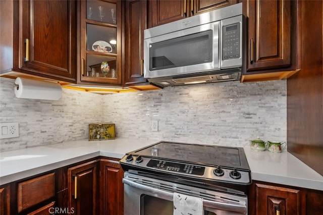 kitchen with dark brown cabinetry, stainless steel appliances, and decorative backsplash