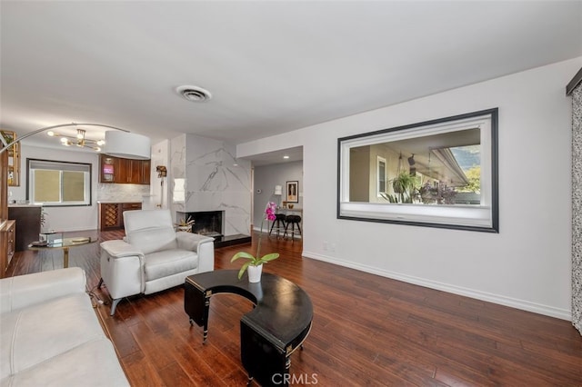 living room with dark hardwood / wood-style floors, an inviting chandelier, and a high end fireplace