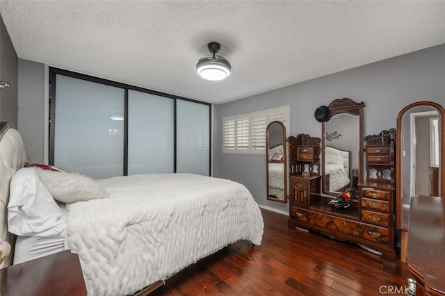 bedroom with ceiling fan, a textured ceiling, dark hardwood / wood-style flooring, and a closet