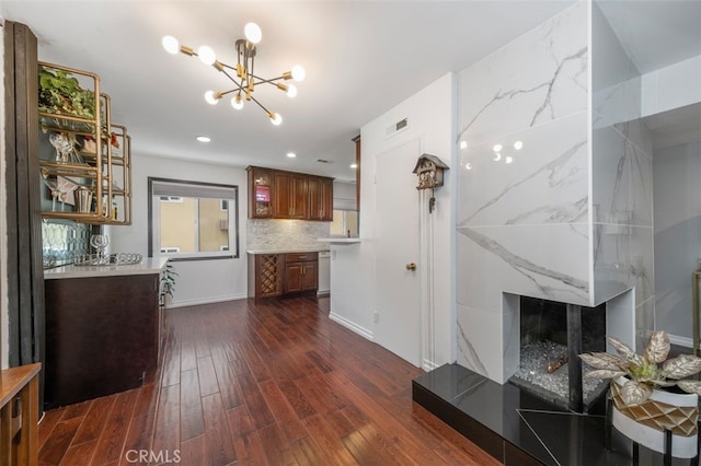 kitchen with an inviting chandelier, backsplash, white dishwasher, a fireplace, and dark hardwood / wood-style flooring