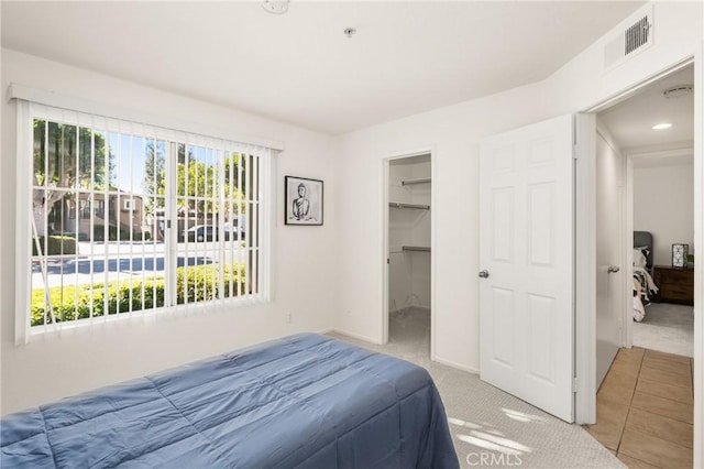 carpeted bedroom featuring a walk in closet and a closet