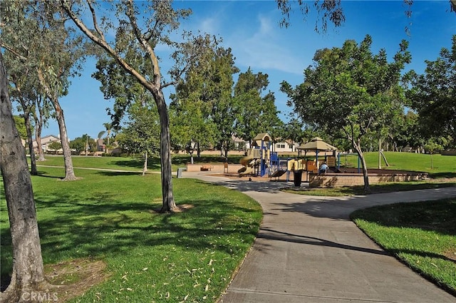 view of home's community featuring playground community and a yard