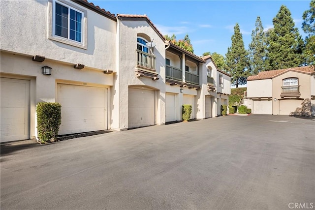 view of front of property featuring a garage, a tile roof, a residential view, and stucco siding