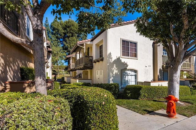 view of front of property with a tiled roof, a balcony, and stucco siding