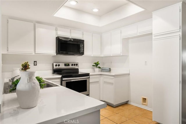 kitchen featuring white cabinets, a tray ceiling, stainless steel range with electric cooktop, and light tile patterned flooring