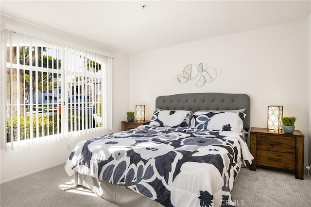 bedroom featuring baseboards, multiple windows, and light colored carpet