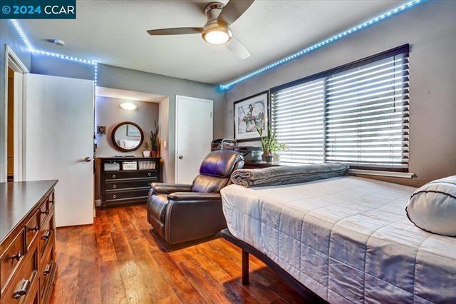 bedroom with ceiling fan, dark hardwood / wood-style flooring, and multiple windows