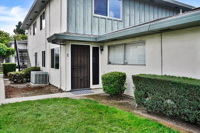 view of exterior entry with cooling unit and a yard