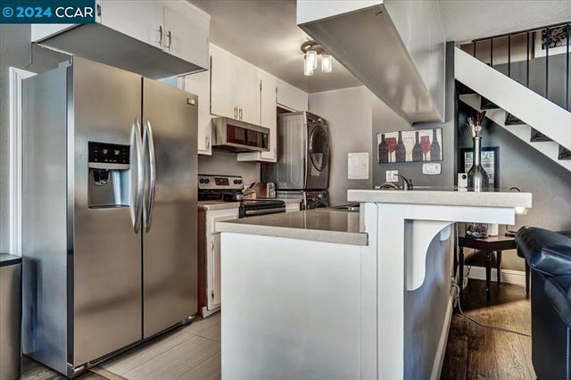 kitchen featuring a kitchen bar, kitchen peninsula, white cabinets, and stainless steel appliances