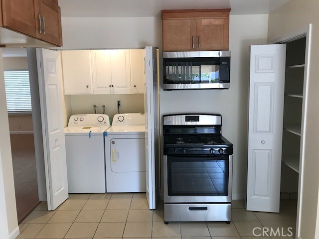 laundry area with cabinets, separate washer and dryer, and light tile patterned floors