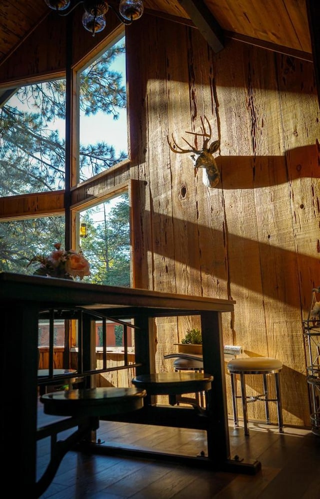 bar with wooden walls, lofted ceiling with beams, and hardwood / wood-style floors