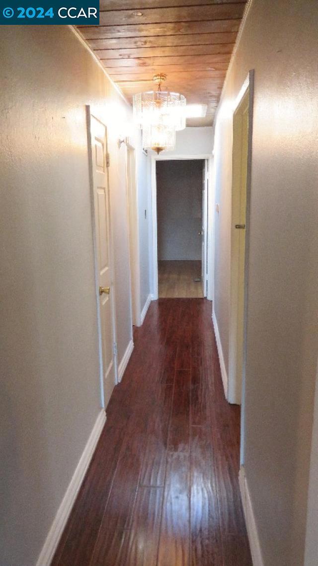 hallway featuring a chandelier, dark hardwood / wood-style flooring, and wooden ceiling