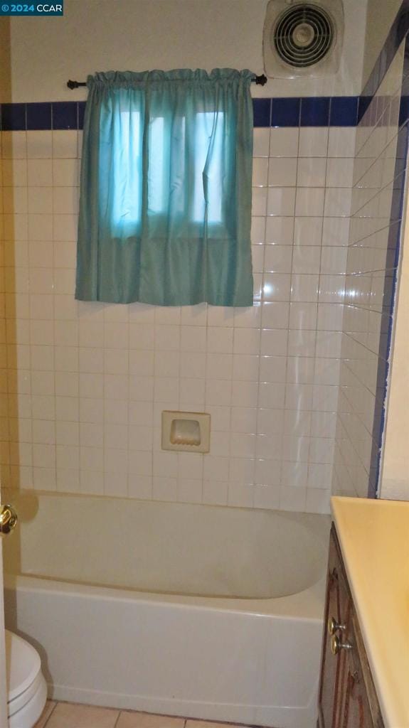 full bathroom featuring tiled shower / bath, tile patterned flooring, vanity, and toilet