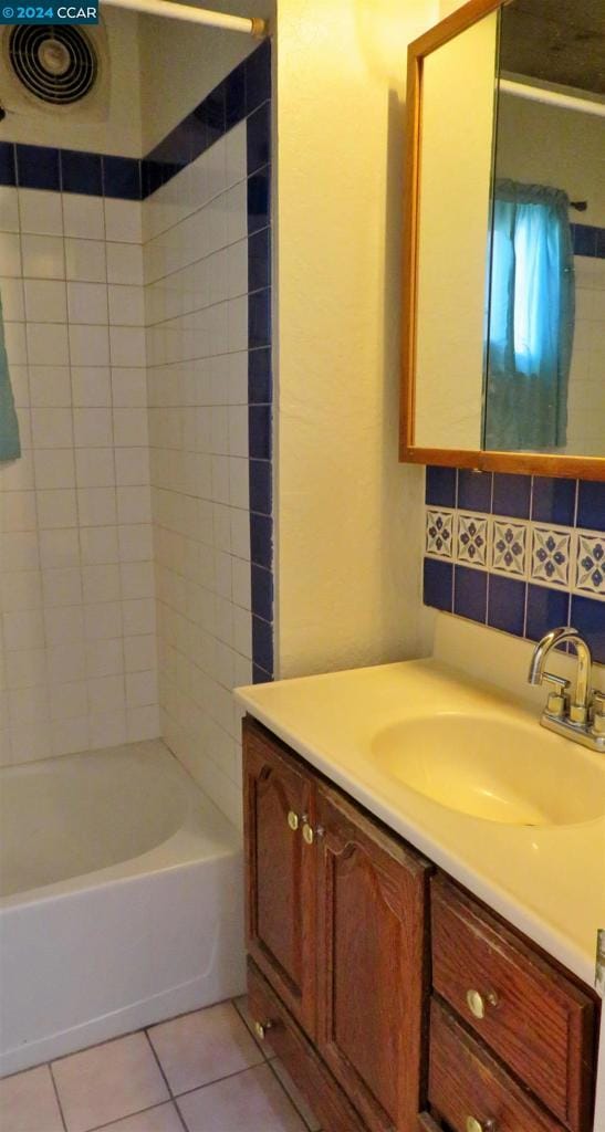 bathroom featuring tile patterned floors, vanity, tiled shower / bath, and tasteful backsplash