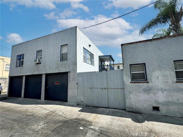 833 E 1st St, Long Beach, CA 90802 - view of side of home featuring stucco siding, a garage, fence, driveway, and cooling unit