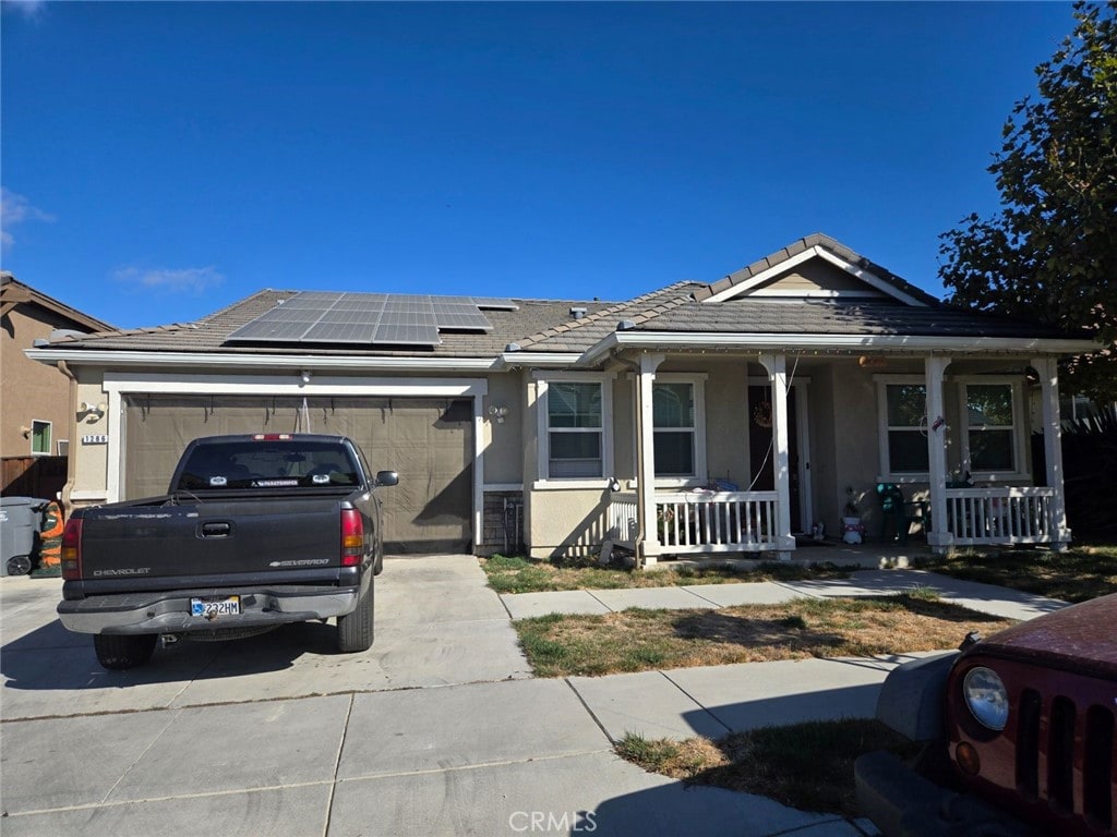 view of front of property featuring solar panels, a porch, and a garage