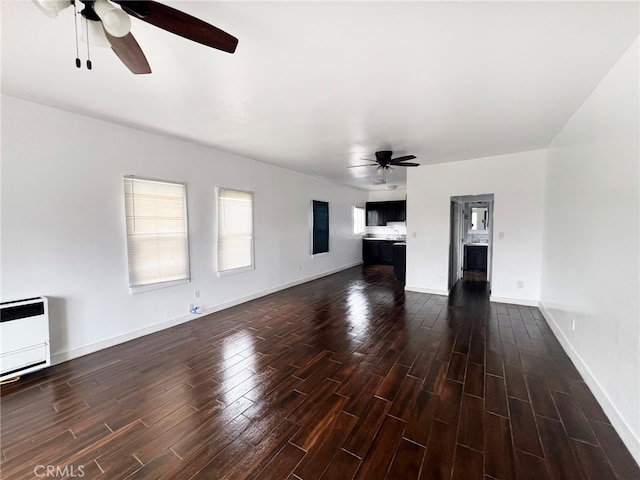 unfurnished living room with dark wood-type flooring, heating unit, and ceiling fan