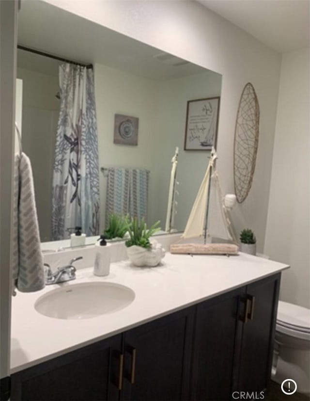 bathroom with a shower with shower curtain, vanity, and toilet