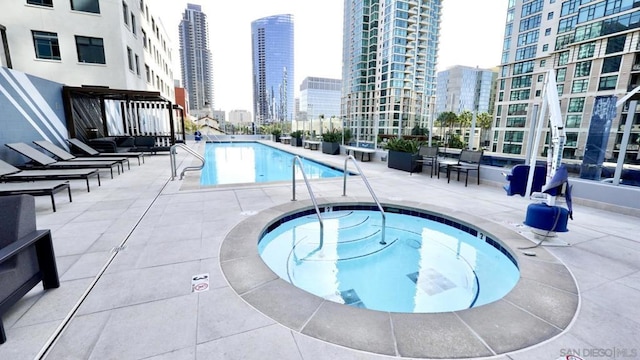 view of pool with a hot tub and a patio area