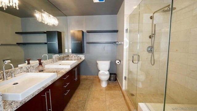 bathroom featuring vanity, an inviting chandelier, tile patterned flooring, toilet, and a shower with shower door