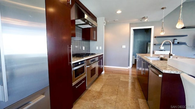 kitchen with tasteful backsplash, light stone counters, stainless steel appliances, sink, and pendant lighting