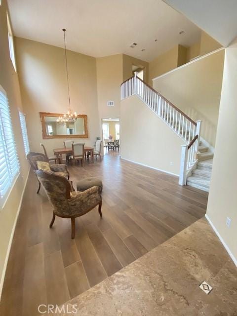 living room featuring hardwood / wood-style flooring, a towering ceiling, and an inviting chandelier