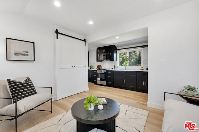 living room with a barn door and light wood-type flooring