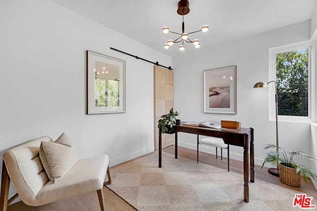 office area with a barn door, a chandelier, and light hardwood / wood-style floors