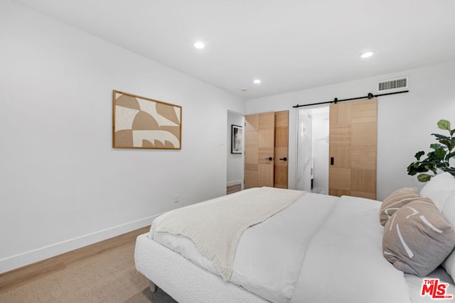 bedroom featuring hardwood / wood-style floors and a barn door