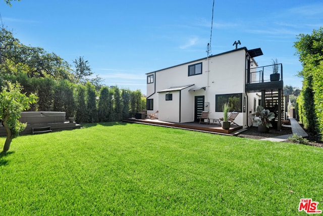 rear view of house featuring a yard, a hot tub, and a wooden deck