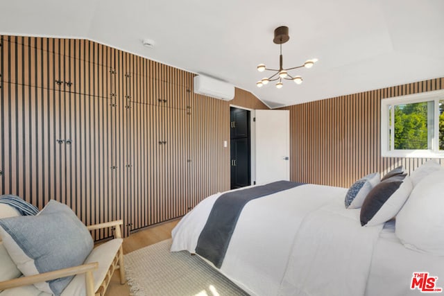 bedroom with a wall mounted AC, a chandelier, vaulted ceiling, wooden walls, and light wood-type flooring