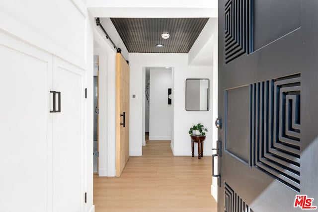 hall featuring light wood-type flooring and a barn door