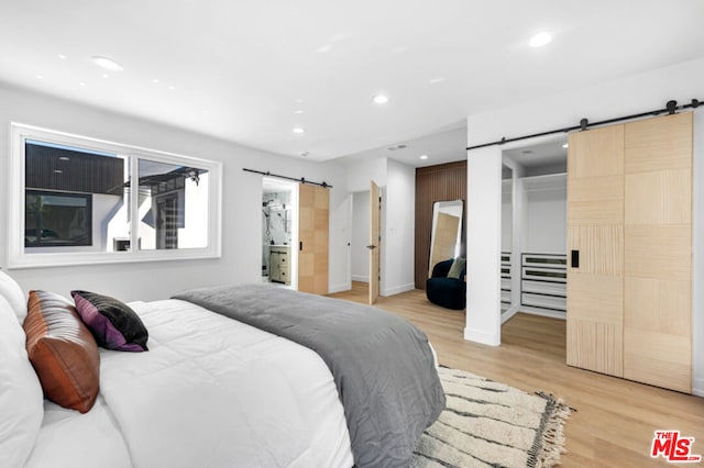 bedroom with light wood-type flooring and a barn door