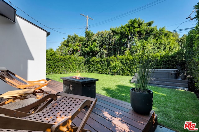 deck featuring a fire pit, a yard, and a hot tub